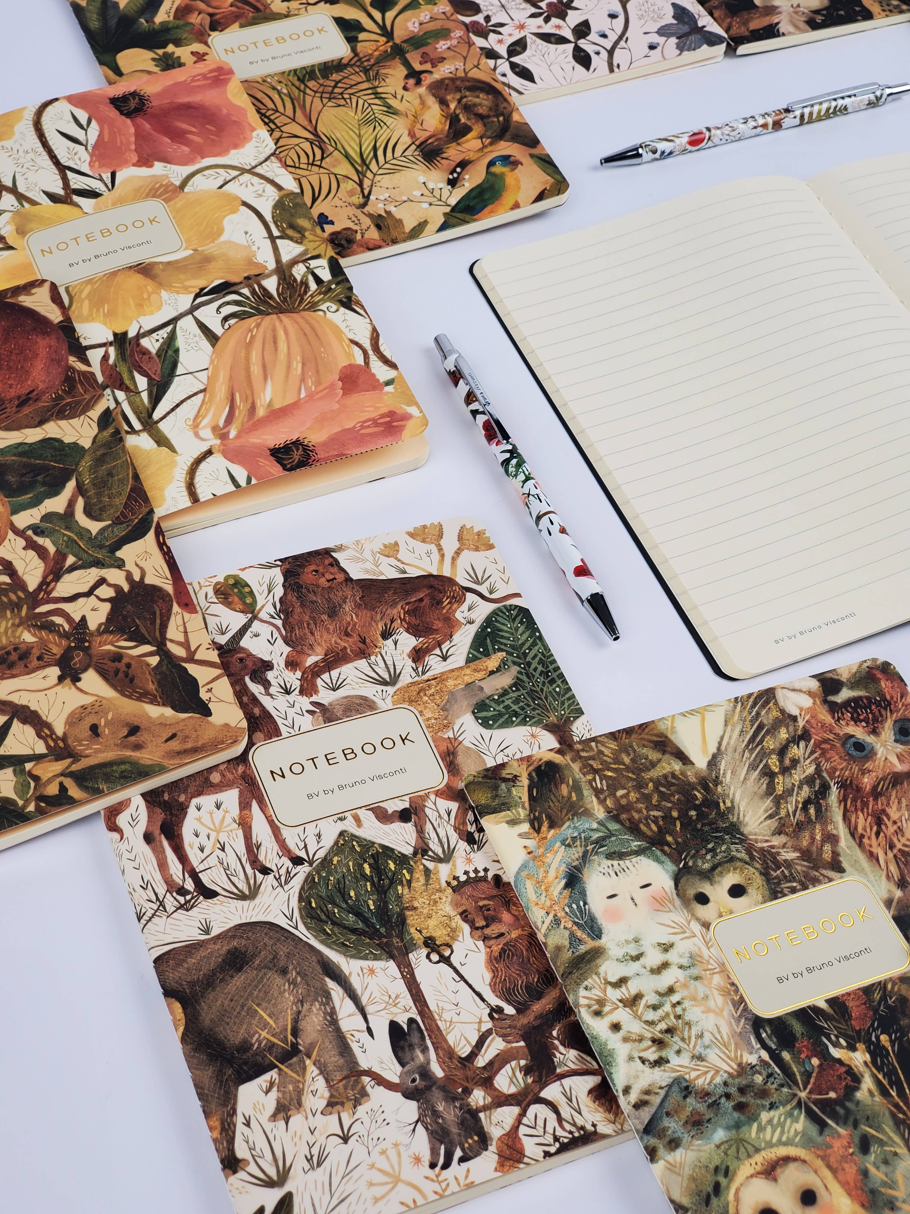 Notebooks with animal-themed covers and a pen on a white surface