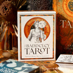 Baddeley Tarot card box with tarot cards and decorative items in the background