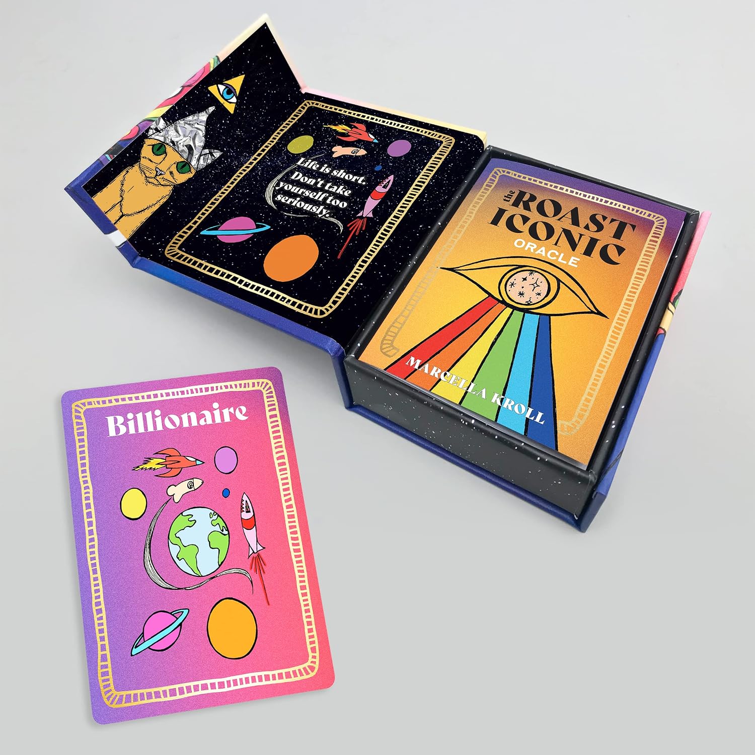 A boxed card game set shown open on a light gray background, with one card placed in front. The packaging and card art feature colorful space-themed illustrations and the visible title 'ROAST ICONIC GAME.