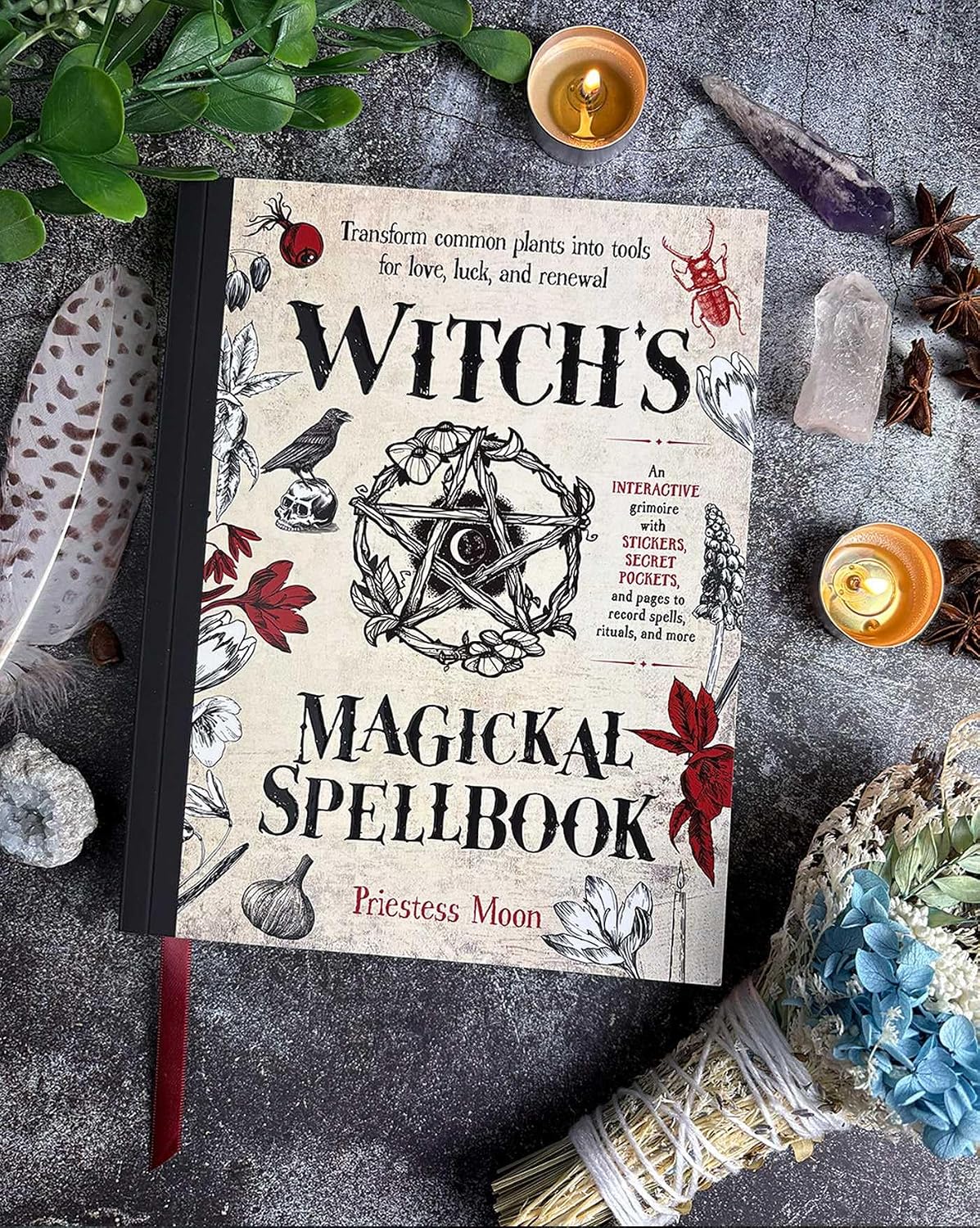 Book titled 'Witch's Magickal Spellbook' surrounded by mystical items on a dark surface.