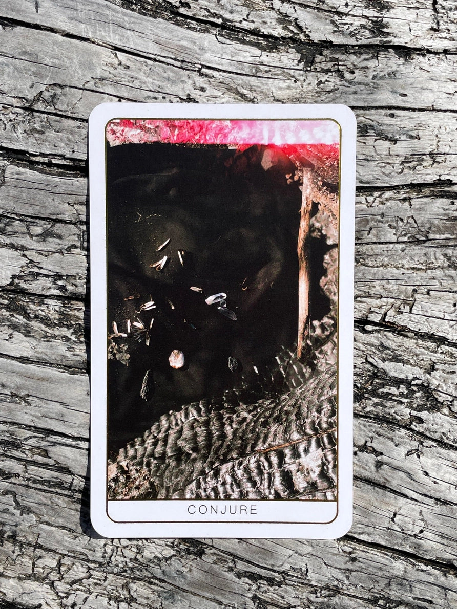 Card with a black cat and text 'Conjure' on a textured wooden background