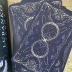 Blue tarot cards with white illustrations on a textured surface