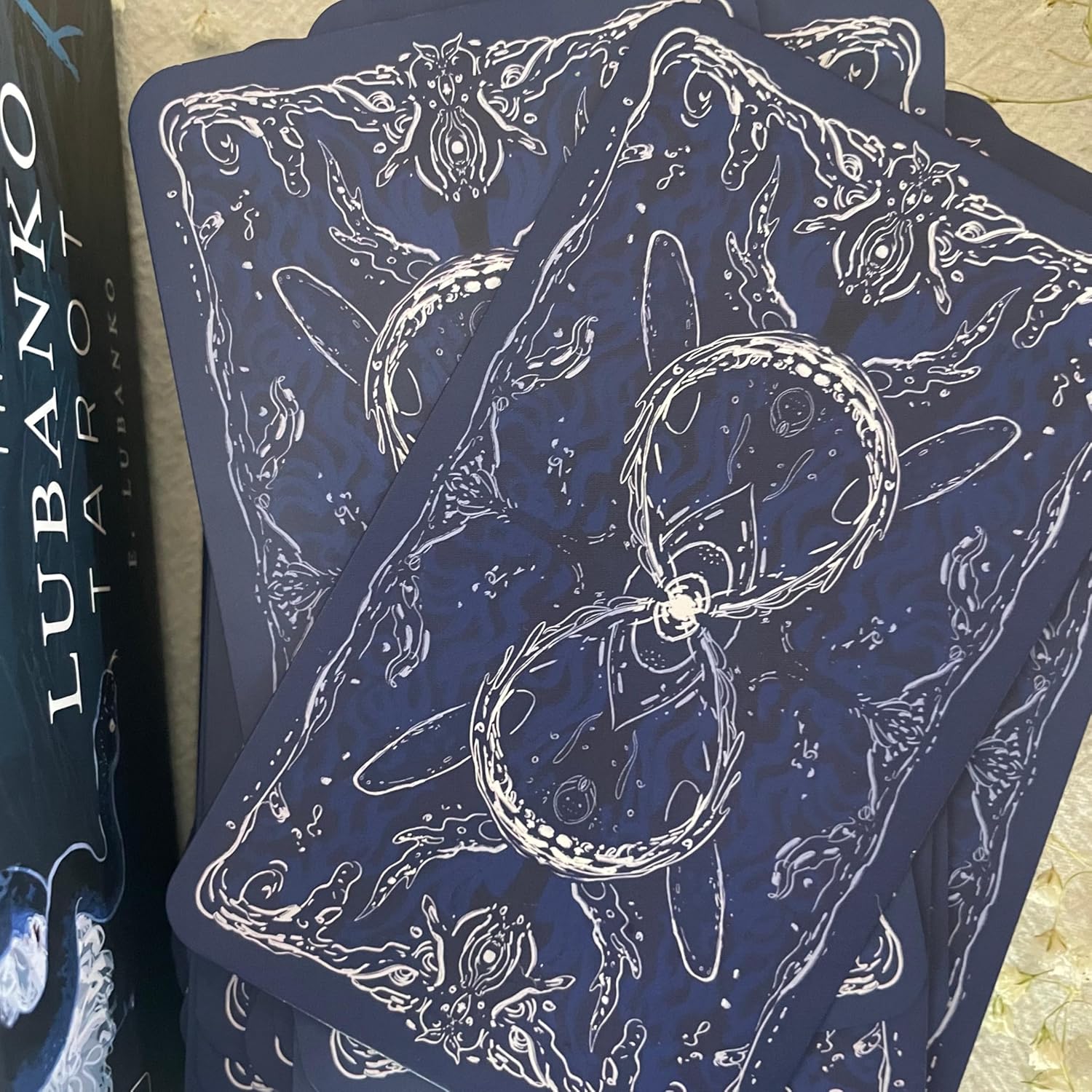 Blue tarot cards with white illustrations on a textured surface