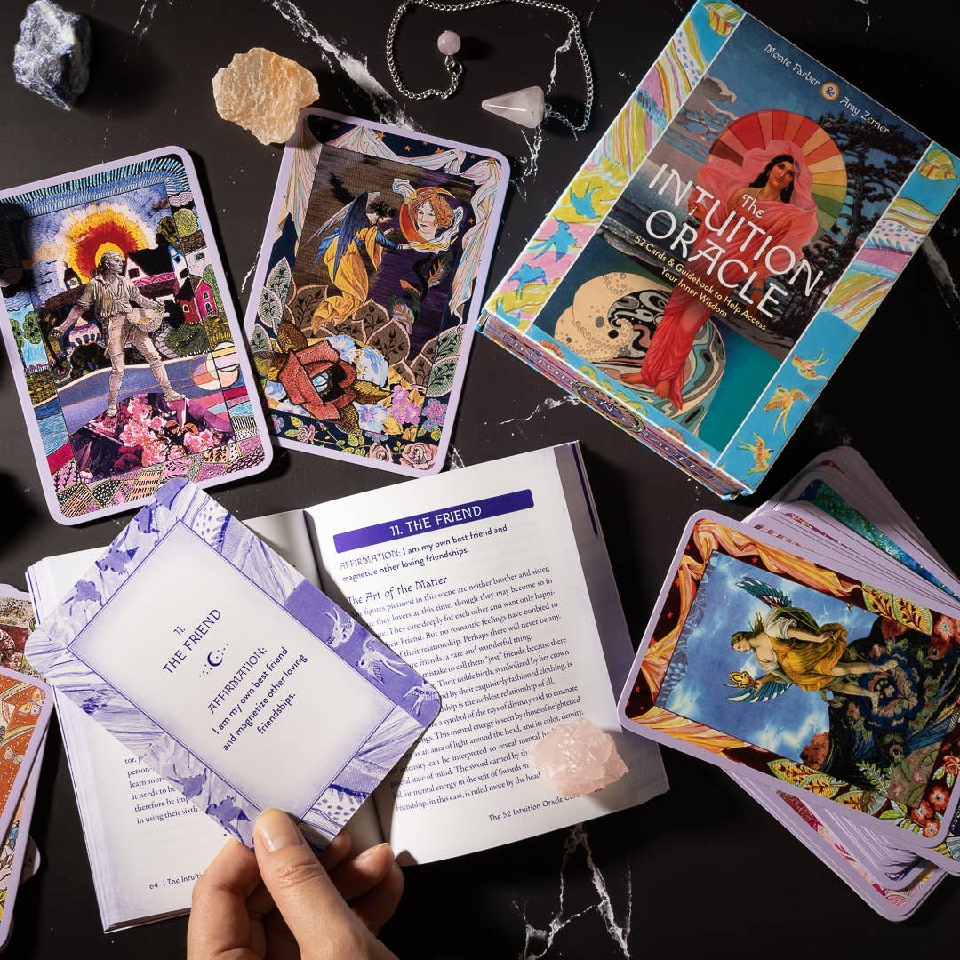 Tarot cards and book on a dark surface with a hand holding a card.