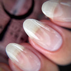 Close-up of manicured fingernails with a glossy, sheer white to pale pink gradient tip design.