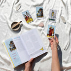 Tarot cards and book on a white fabric surface