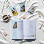 Open book with tarot card illustrations on a white fabric background