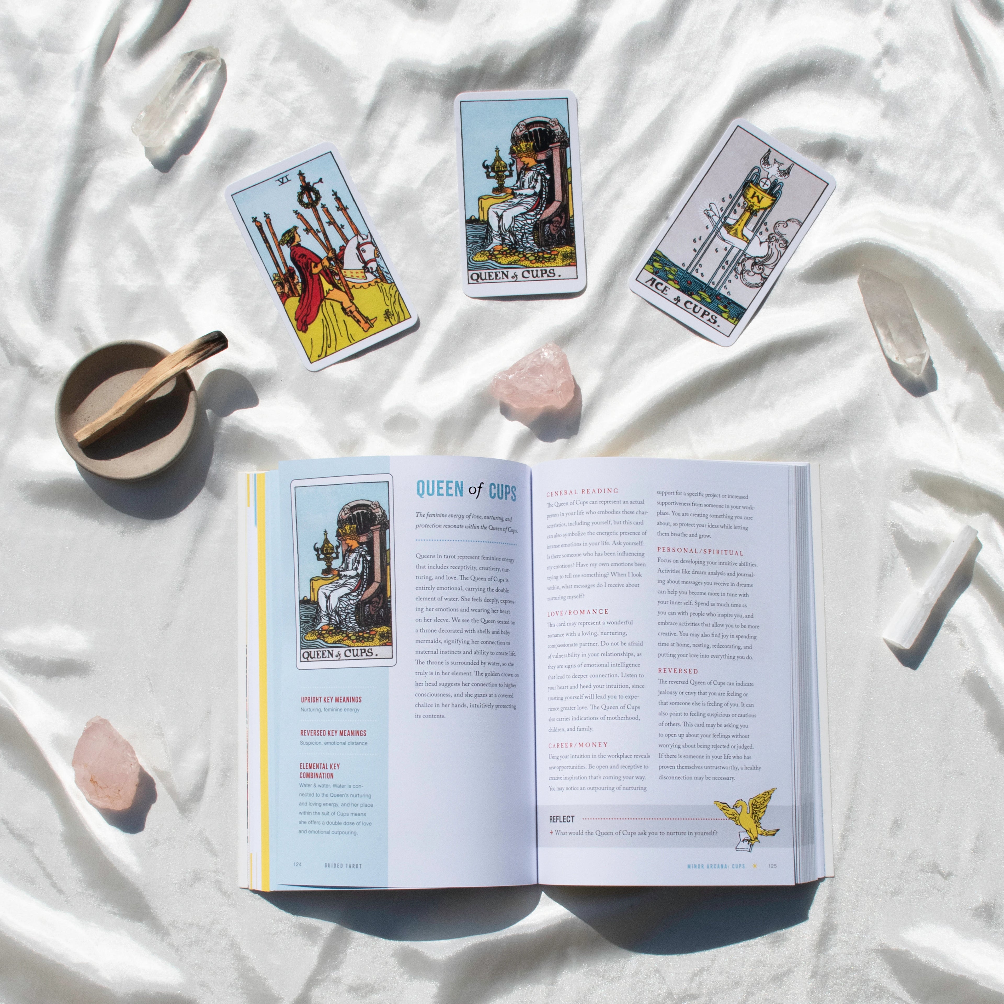 Open book with tarot card illustrations on a white fabric background