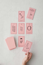 Set of pink tarot cards with black illustrations on a light gray surface.
