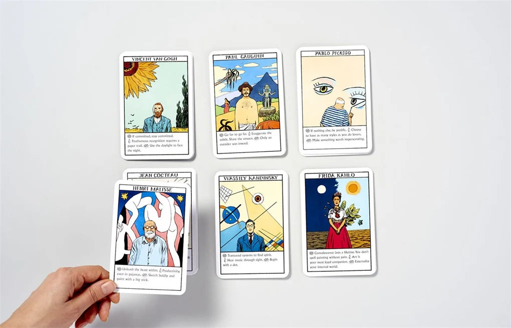Collection of tarot cards displayed on a white surface with a hand holding one card.