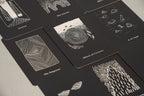 Black tarot cards with white illustrations on a light gray surface