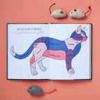 Open book with a colorful cat illustration and text on a pink background, surrounded by small mouse toys.
