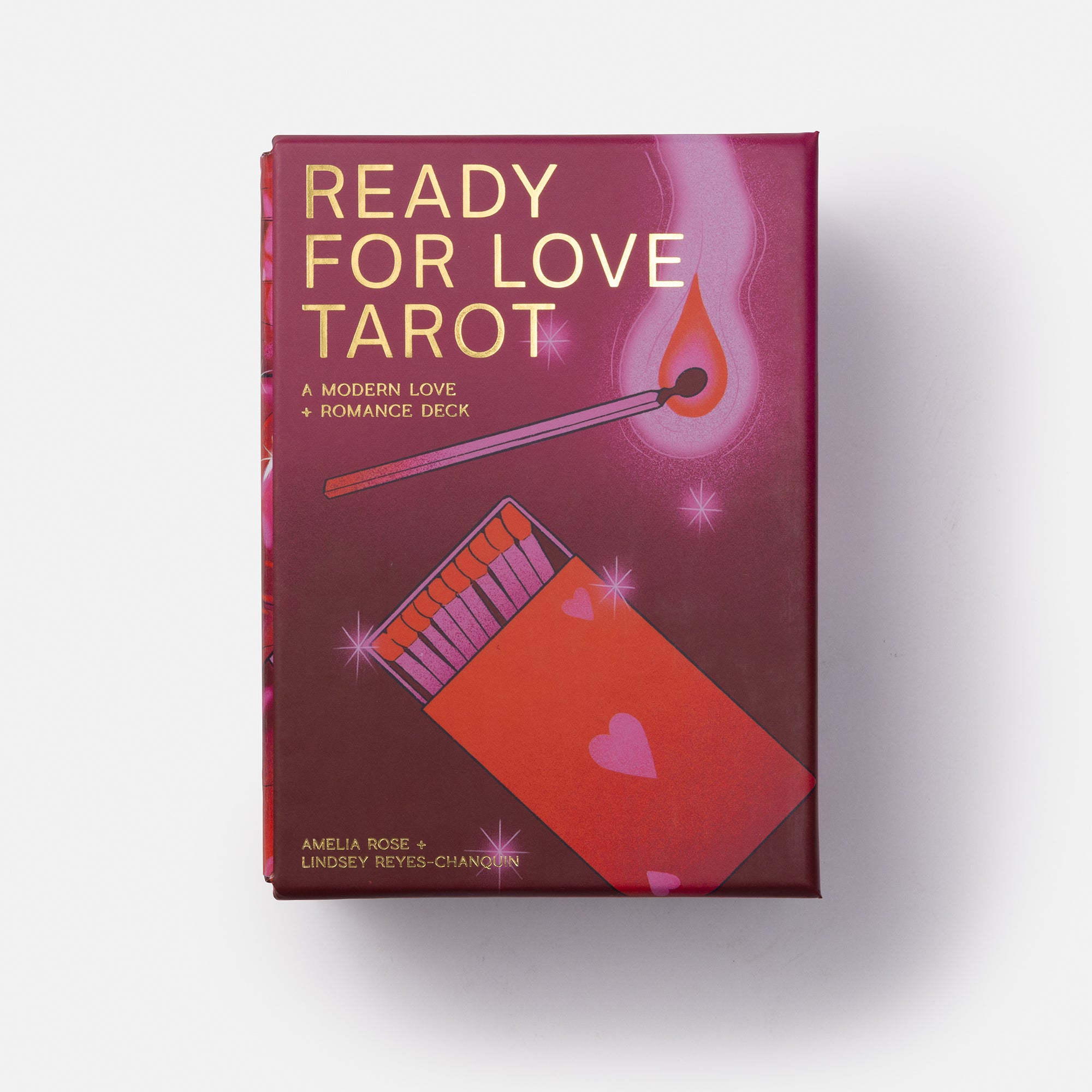 The 'Ready for Love Tarot' deck box by Amelia Ross and Lindsey Reyes-Chang, featuring a deep magenta and purple cover with gold lettering and illustrations of a match and hearts, set against a plain white background.