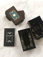 Collection of tarot card boxes with decorative designs on a marble surface