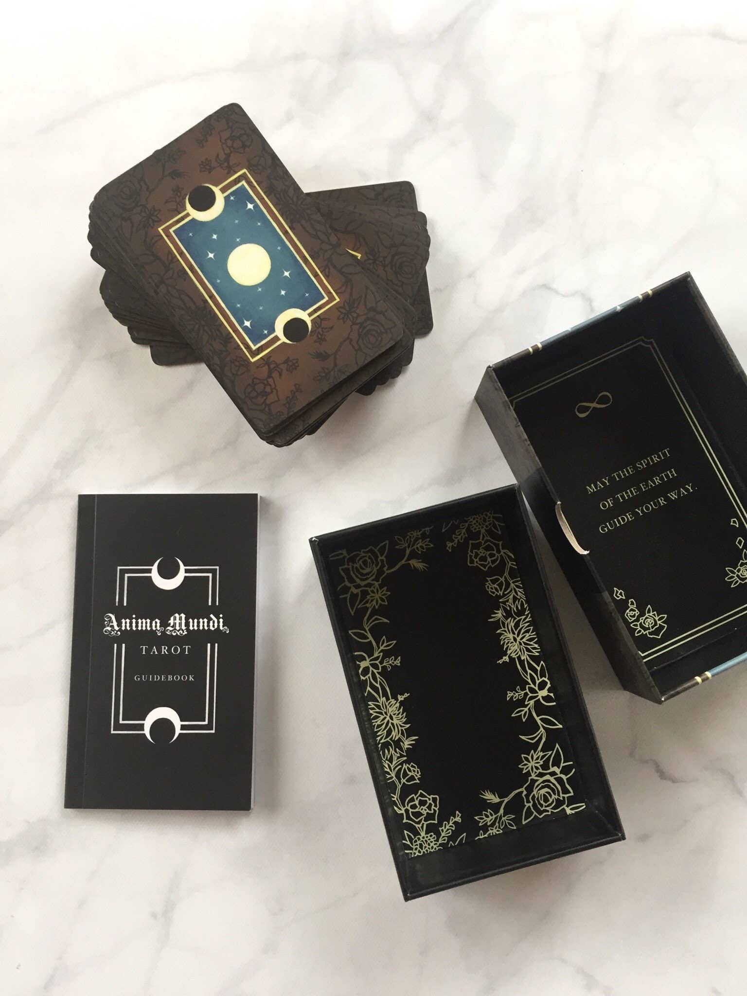 Collection of tarot card boxes with decorative designs on a marble surface