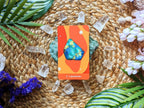 Card with a colorful design of a crystal on a woven surface with crystals and plants.
