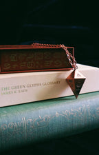 Stack of books with a green glyphs glossary on top, featuring a triangular object.