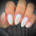 Close-up of a hand with pink and white gradient nails wearing gold rings.