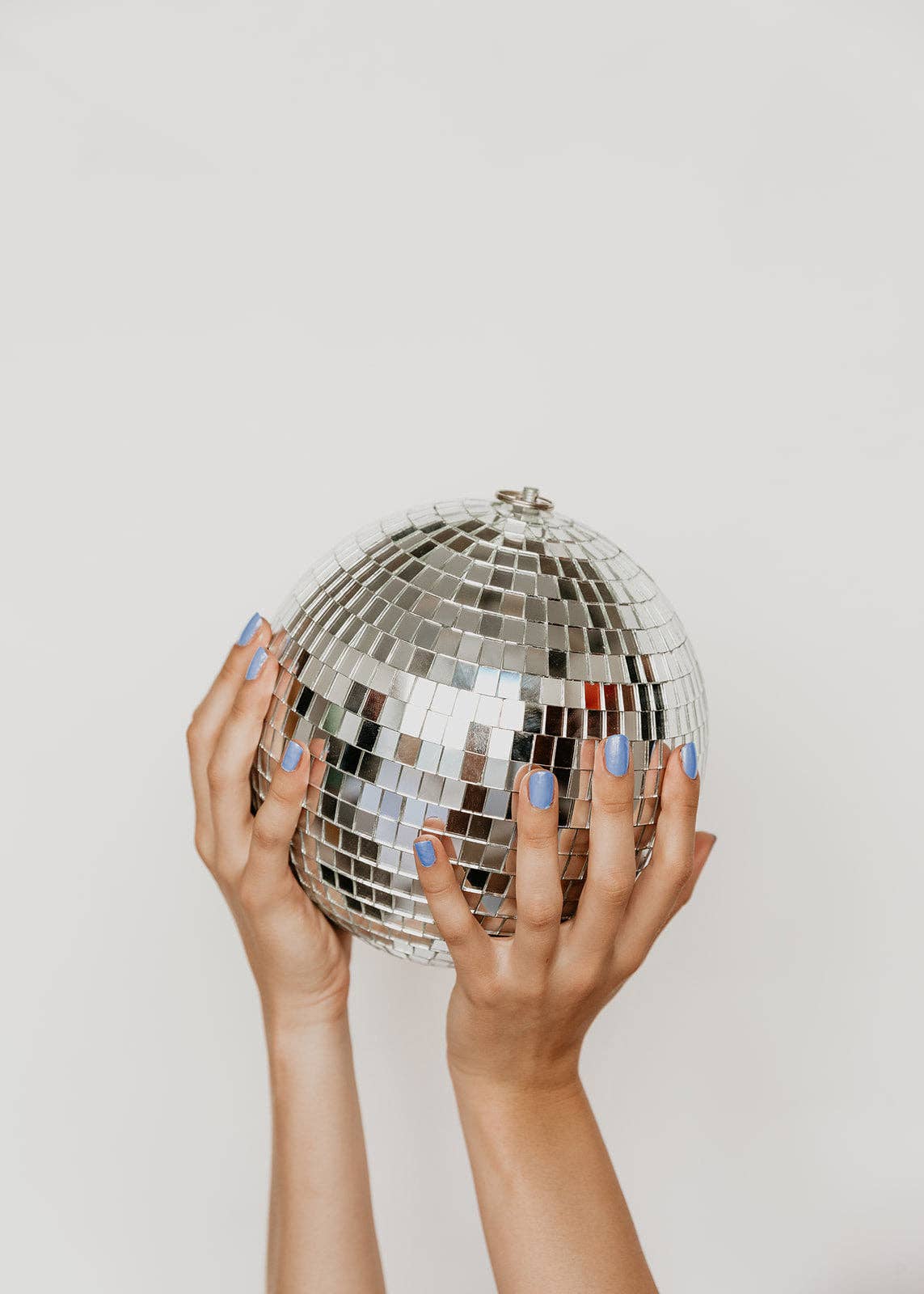 Hands holding a disco ball against a plain background