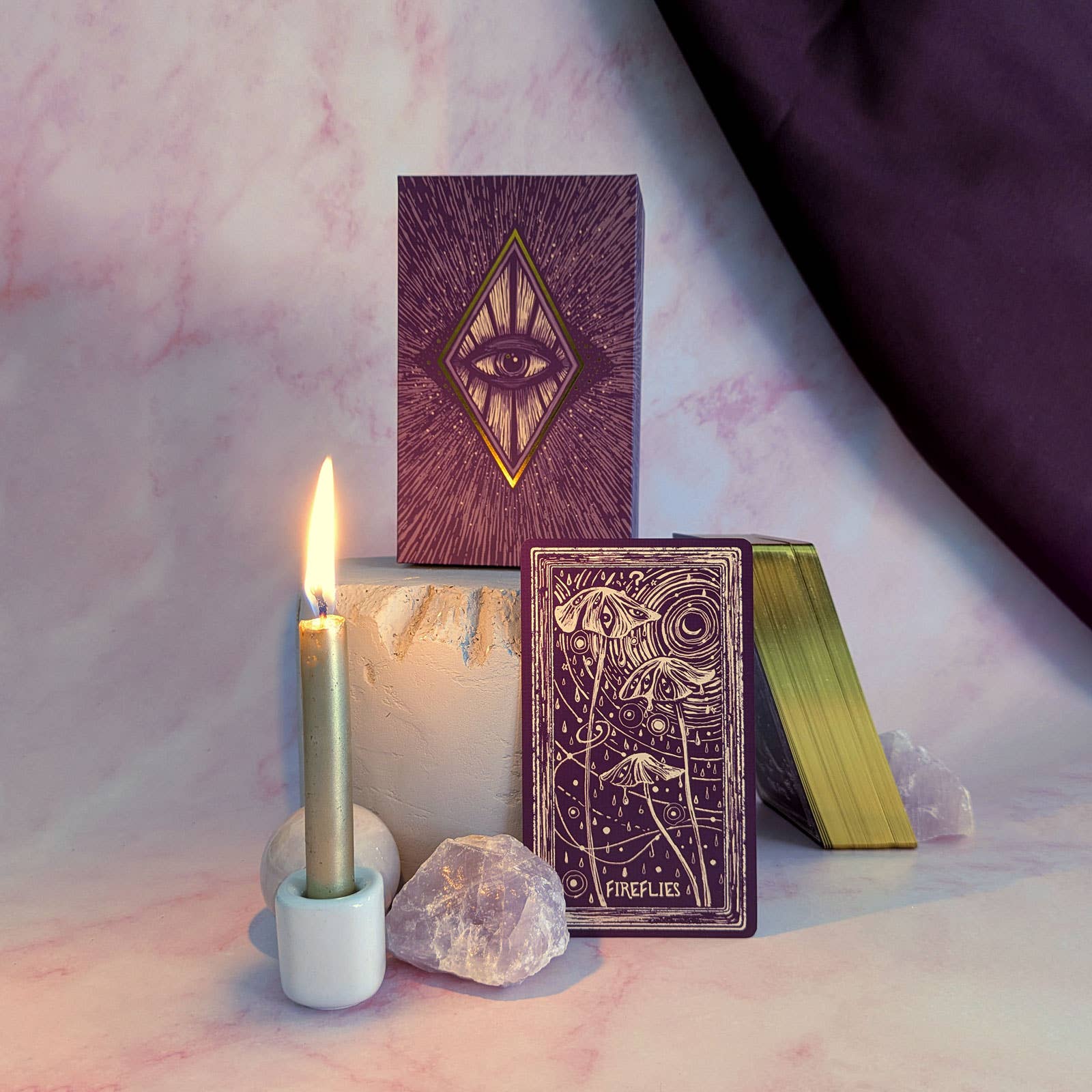 Magical setup with tarot cards, candle, and crystals on a soft pink background