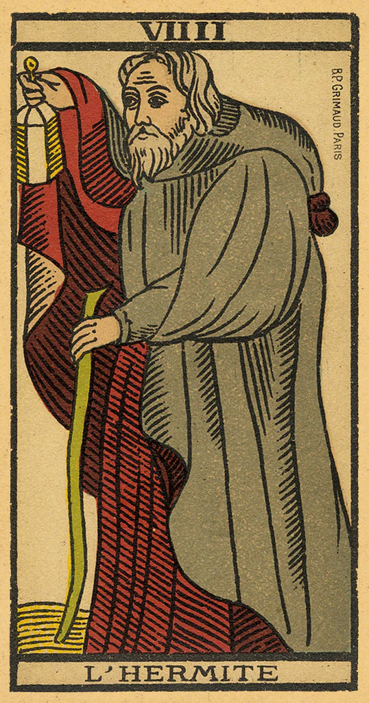 Card from a tarot deck featuring an elderly man with a beard, holding a staff, on a beige background.