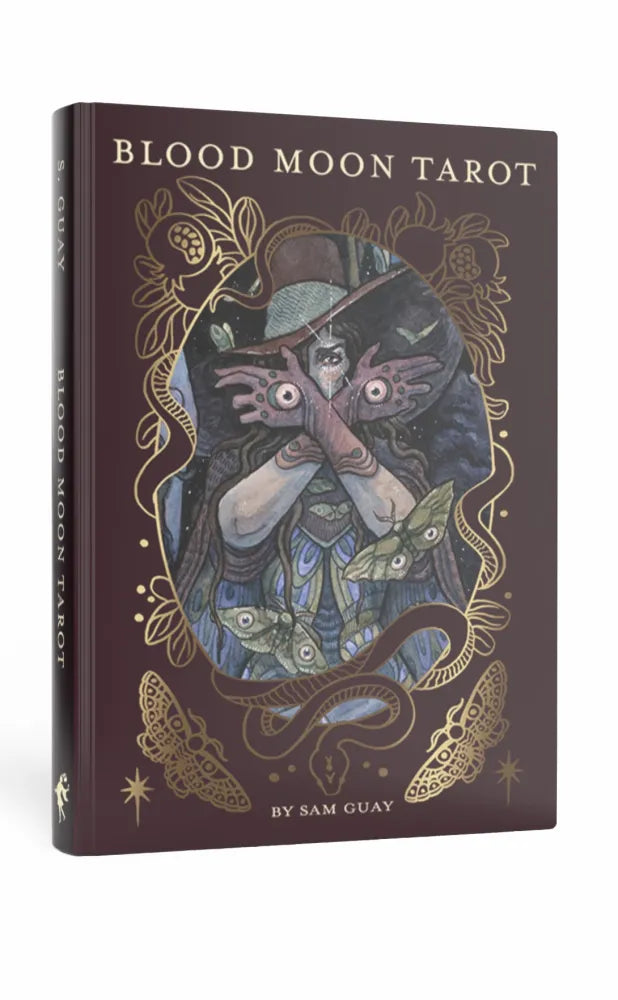 Book titled 'Blood Moon Tarot' with a cover illustration of a person with hands over eyes and decorative elements.