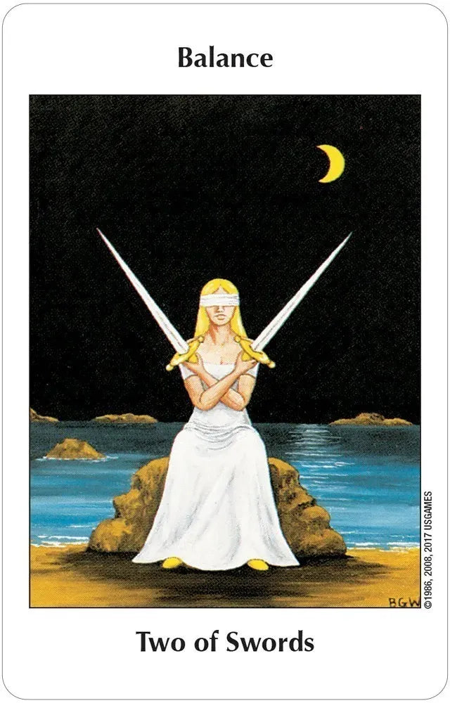 Tarot card titled 'Two of Swords' featuring a woman with two swords on a beach at night.