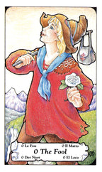 Card from a tarot deck featuring 'The Fool' with a person in a red dress and brown hat holding a white rose.
