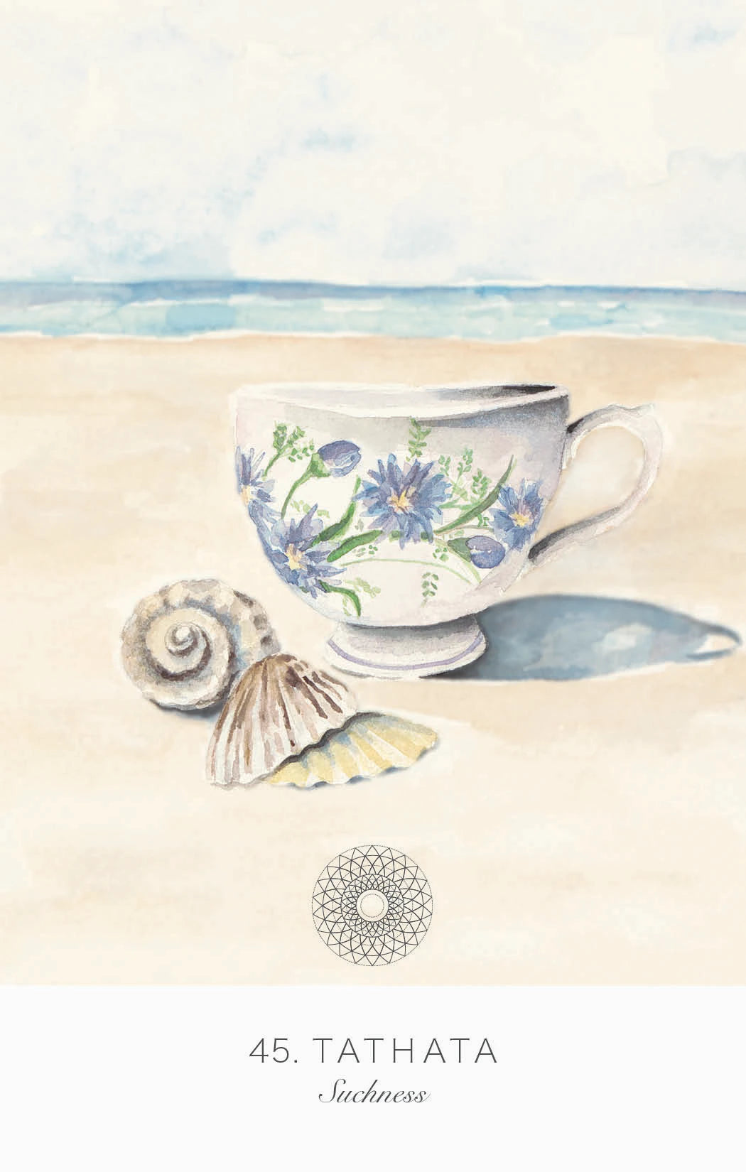 Decorative teacup with floral design on sand with shells and ocean in background, Tathata brand visible.