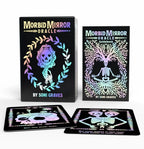 Morbid Mirror Oracle deck box, guidebook, and two cards displayed on a white background. The items feature black bases with holographic rainbow foil artwork of a skull and skeleton.