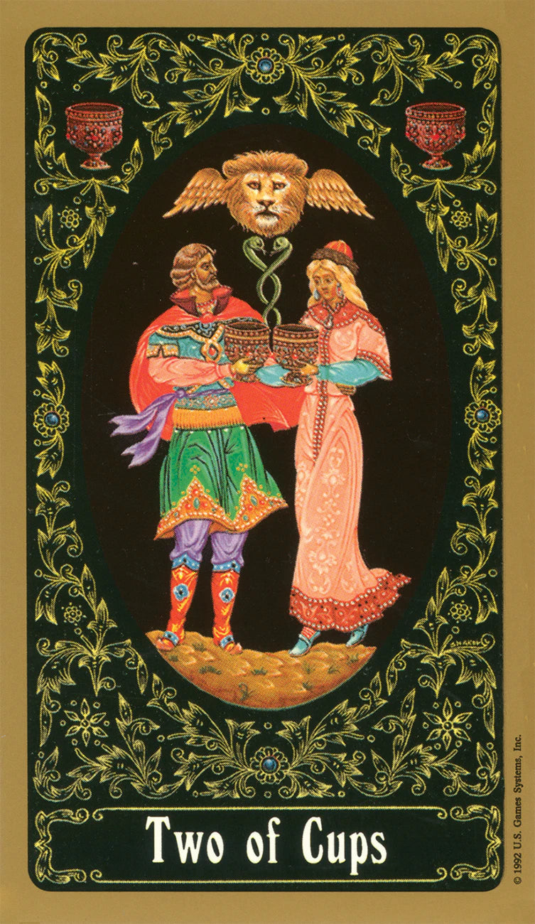 Two of Cups tarot card with decorative border and figures holding cups.