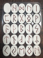 Set of white stones with redRunes on a wooden surface