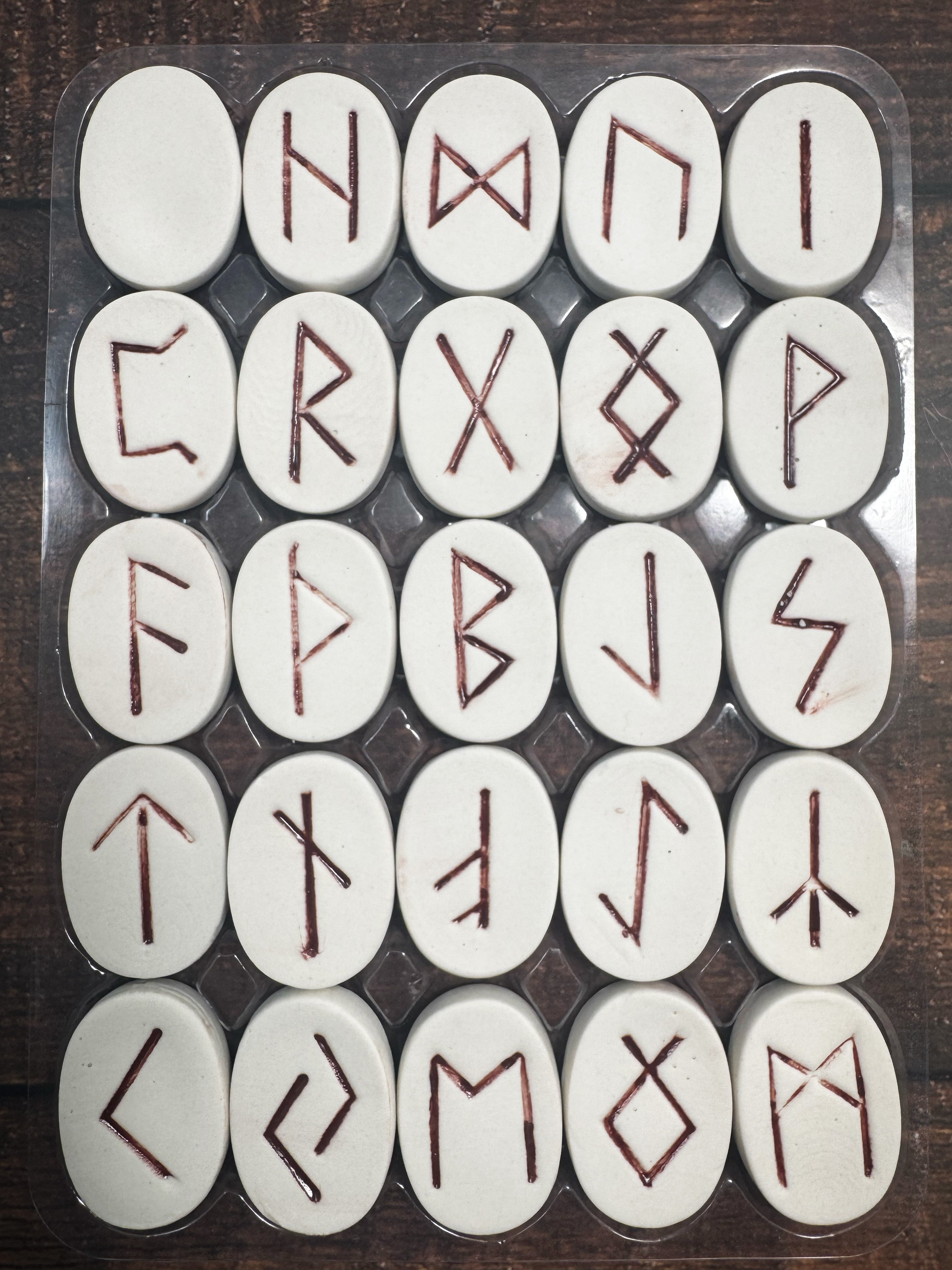 Set of white stones with redRunes on a wooden surface