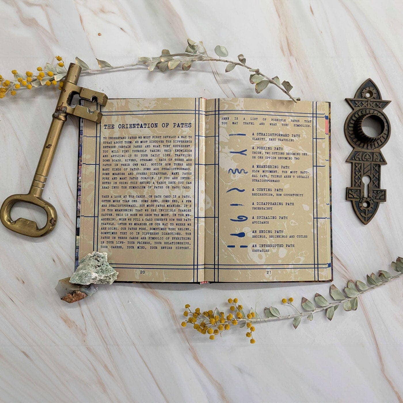 Open book with text and illustrations on a marble surface with decorative elements