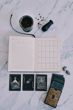 Open notebook with tarot cards and a deck on a marble surface