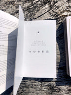 White book with 'Rituals, Practices, Meditations' on a textured surface