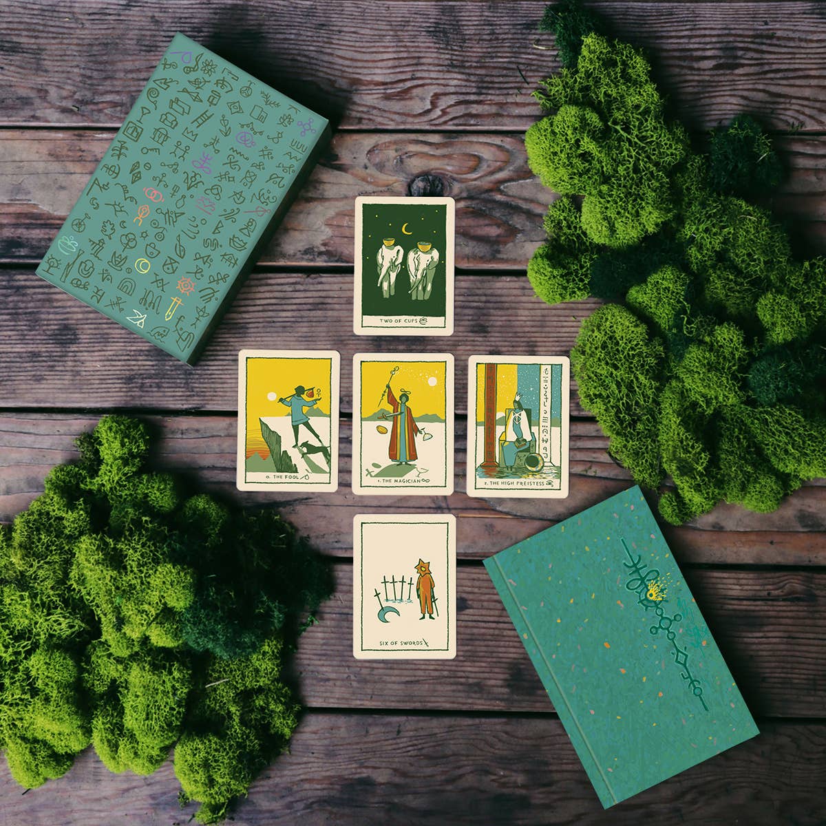 Set of tarot cards on a wooden surface with greenery