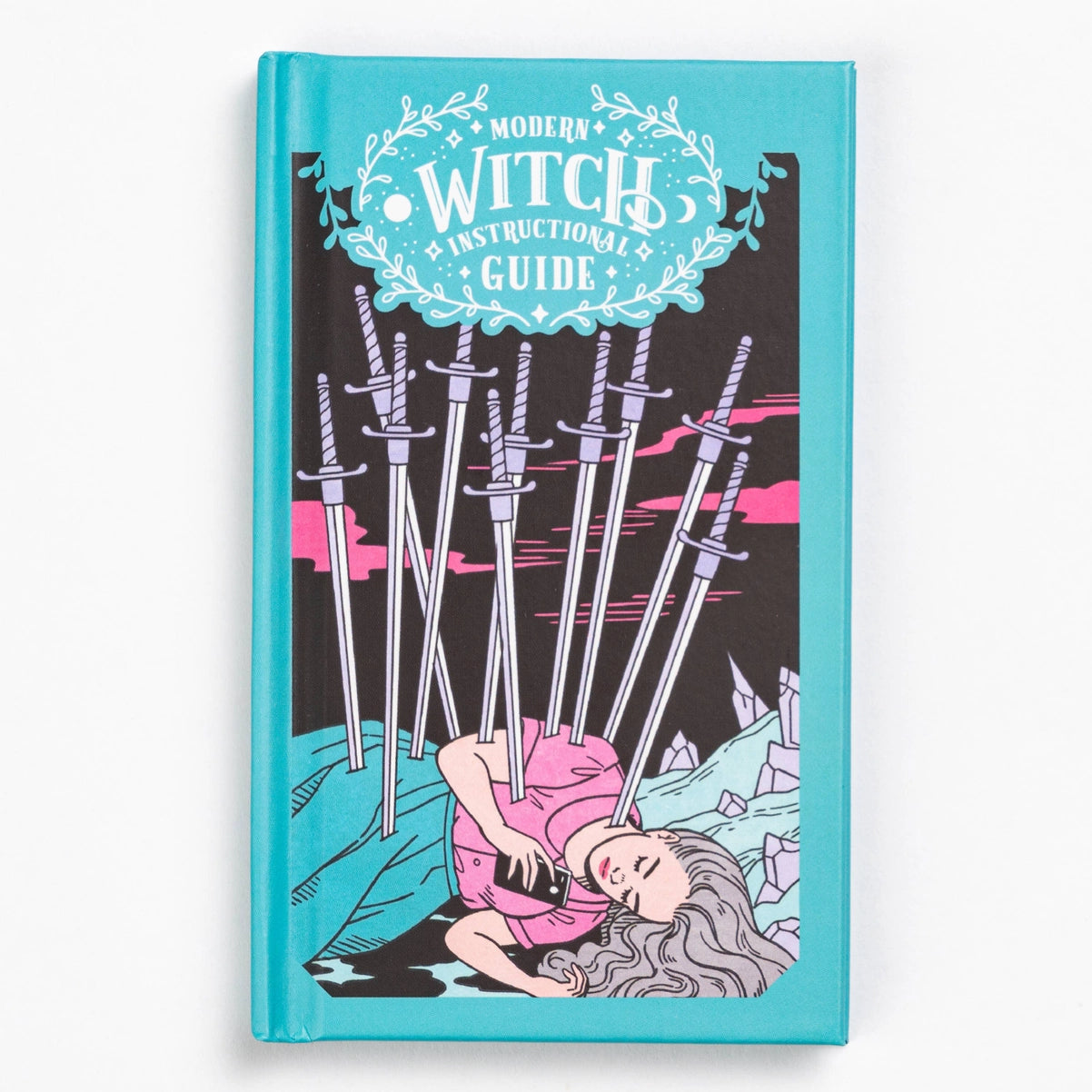 Book titled 'Modern Witch Instructional Guide' with a design of a woman lying on crystals and swords.
