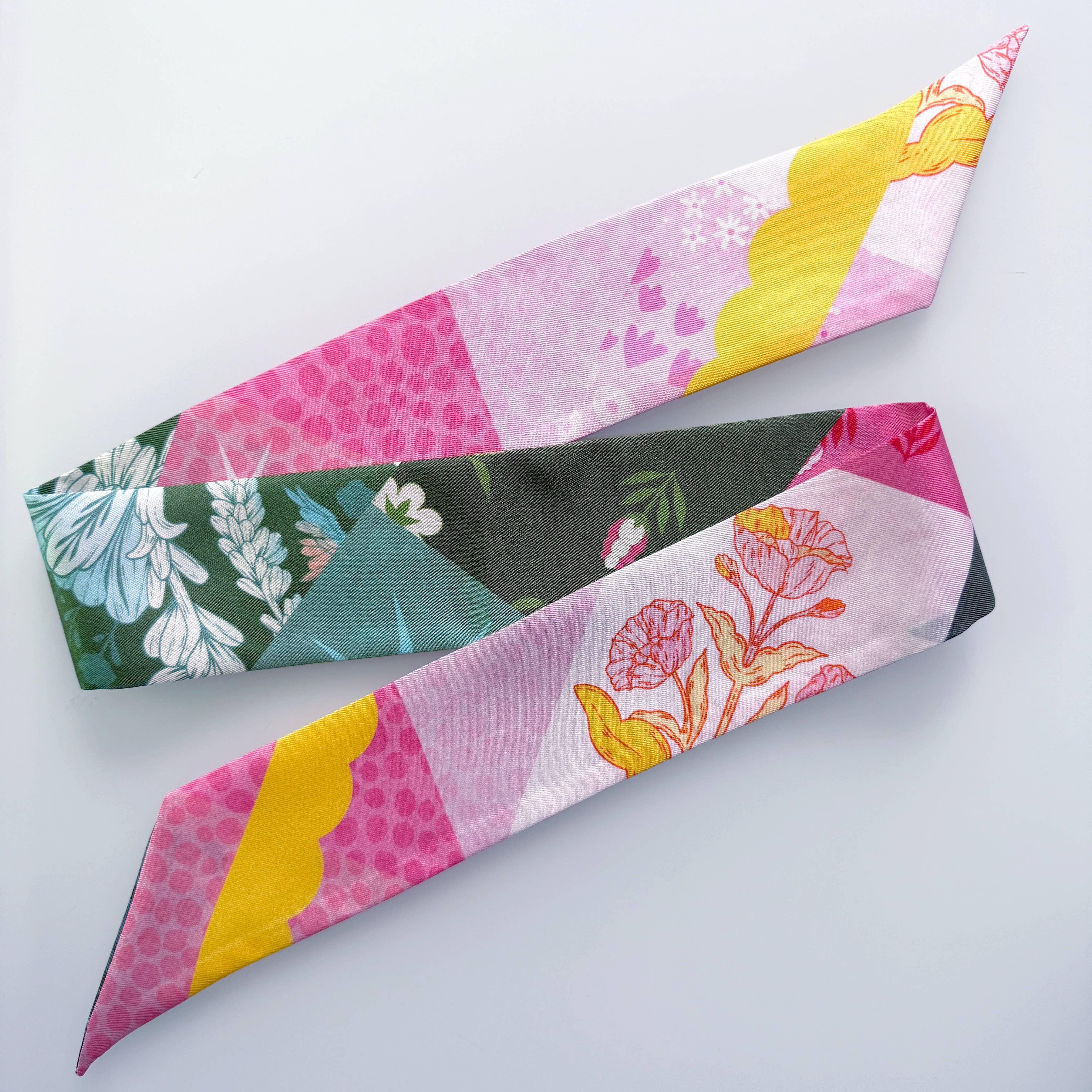Two fabric neckties with colorful patchwork floral and geometric patterns, displayed diagonally on a light gray background.