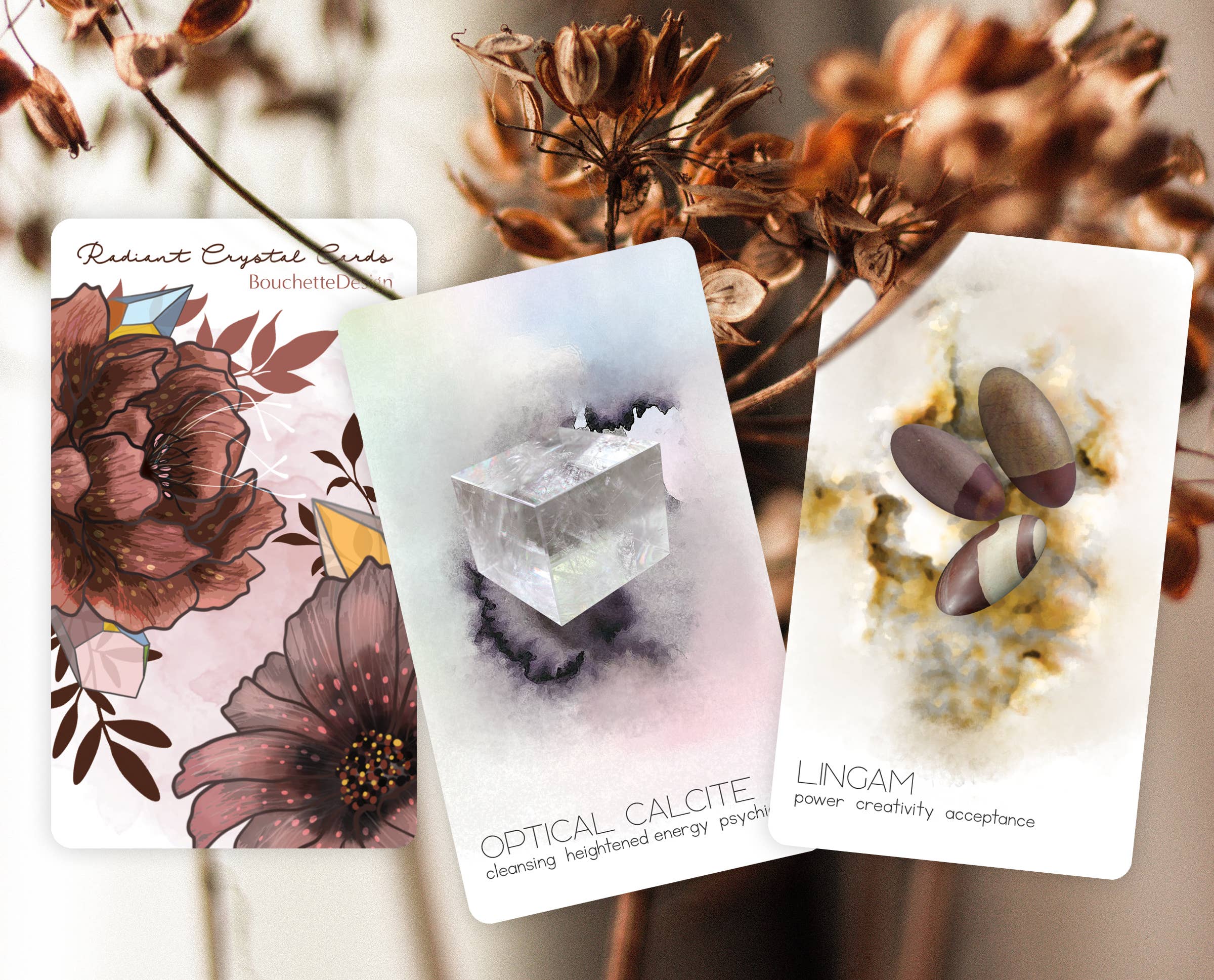 Three tarot cards with floral, crystal, and nature-themed designs on a blurred natural background.