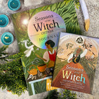 Two books titled 'Seasons of the Witch' on a textured surface with candles and greenery.