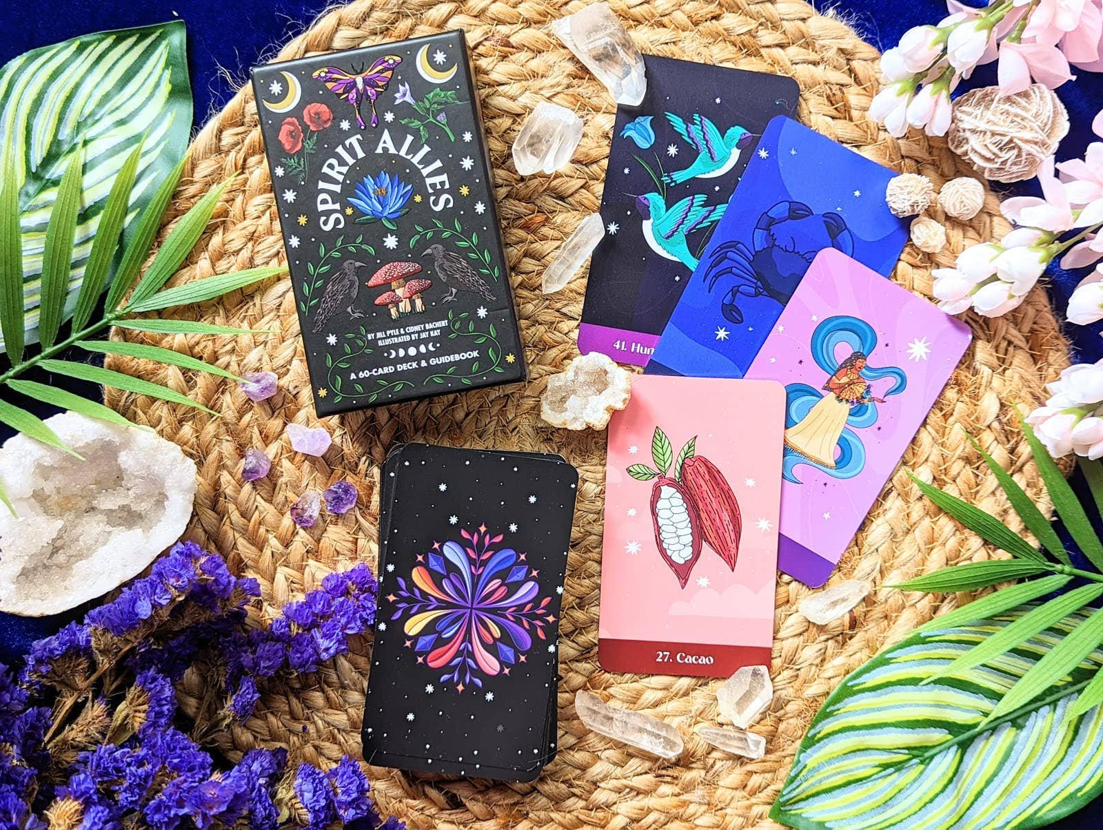 Collection of tarot cards with 'Spirit Allies' branding on a woven mat with plants and crystals.