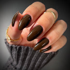 Hand with dark brown nail polish on a blurred background