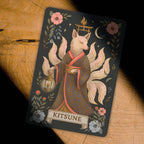 Card featuring a Kitsune with floral and architectural elements on a wooden surface