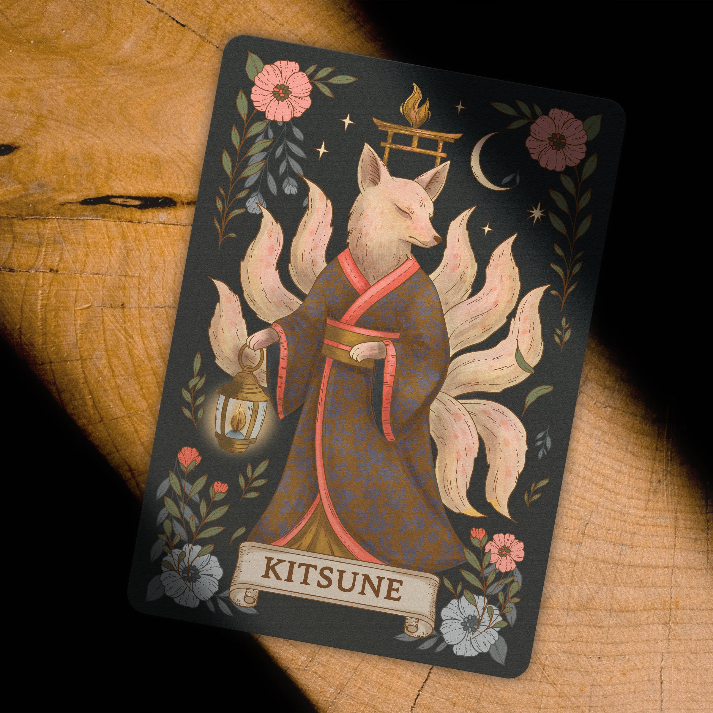Card featuring a Kitsune with floral and architectural elements on a wooden surface
