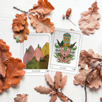 Two playing cards surrounded by autumn leaves on a white background