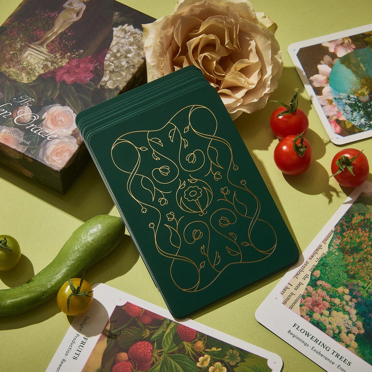 Green notebook with gold floral design on a table with cards and vegetables