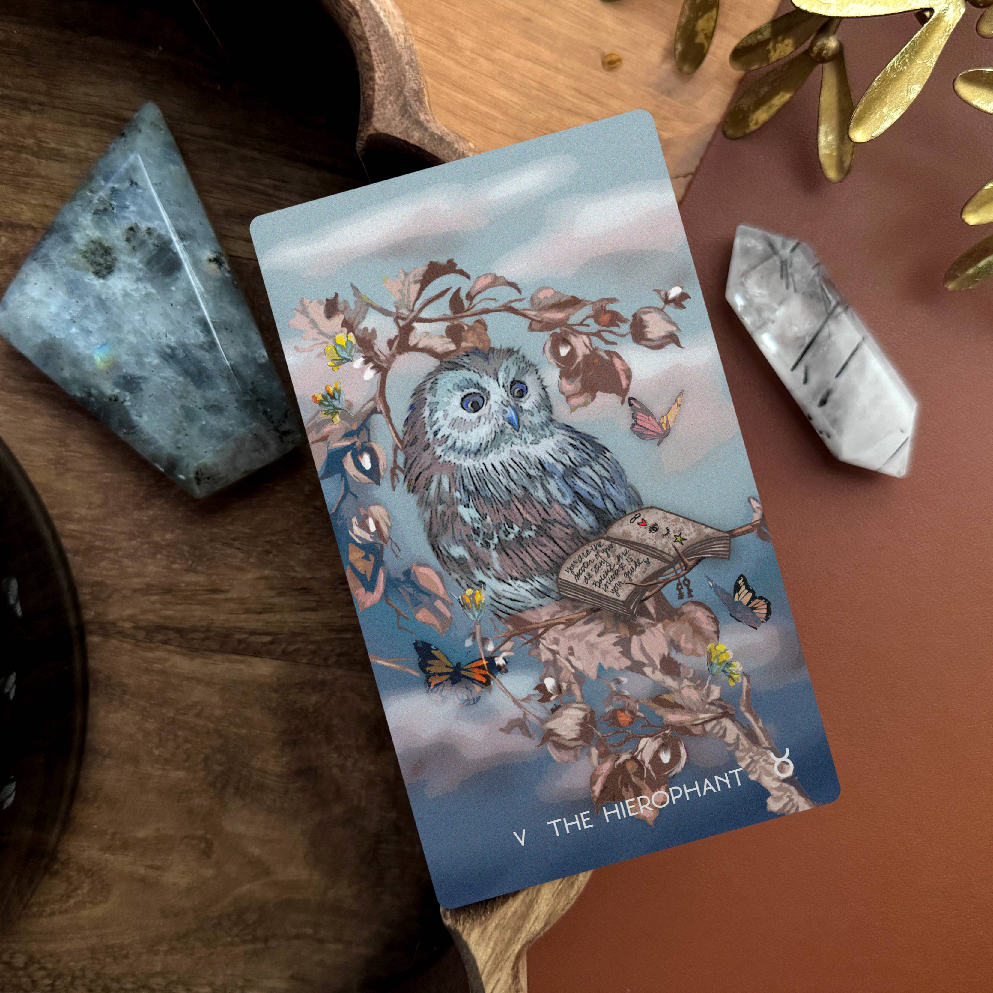 Tarot card featuring an owl with mystical elements on a wooden surface with crystals.