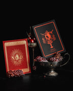 Two decorative cards with intricate designs on a dark background with grapes and a candle.