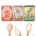 Three salt soaks with packaging featuring nature-themed designs and wooden spoons with salt.